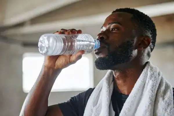 Image of man drinking water to improve hydration Dorset after work out.